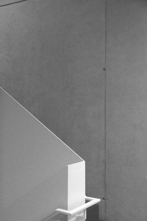 Minimalistisches Innenraum-Design im Gebäudekomplex Neue Siederei mit einer Betonwand und einer modernen, weißen Treppenkonstruktion im Vordergrund.